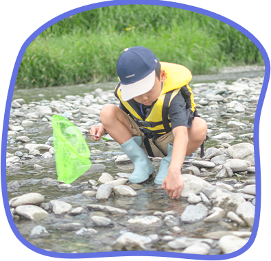 川辺で魚とりをする少年