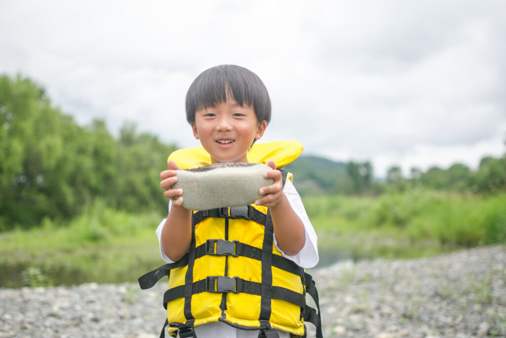 男の子が空知川の大きな石を持っている様子